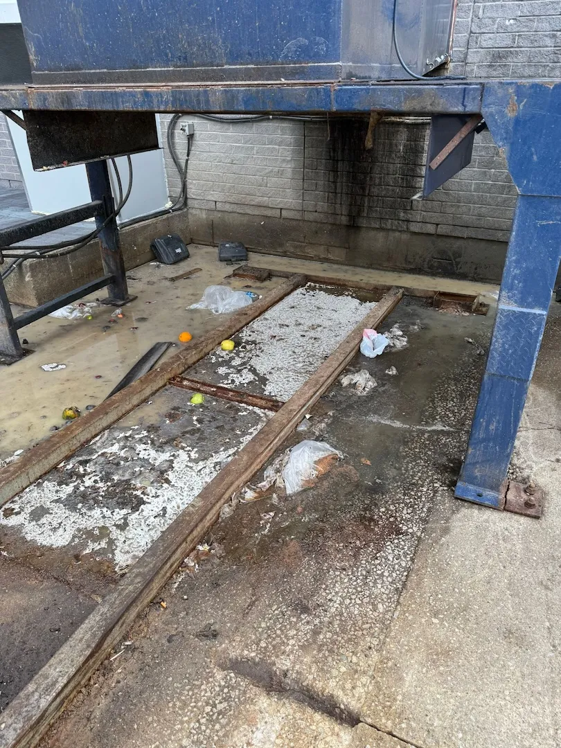 Commercial trash compactor area with waste and debris before professional cleaning service
