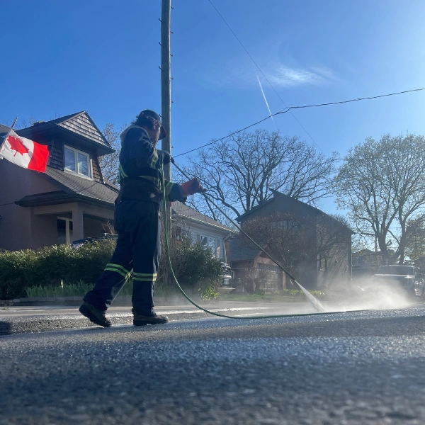 Professional pressure washing on a residential street in Toronto with a Canadian flag visible.