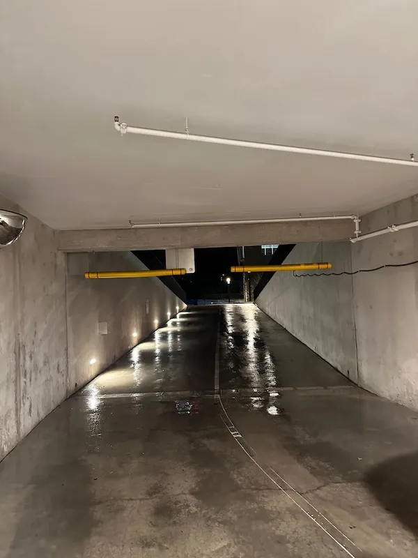 Freshly pressure washed underground garage ramp with wall lighting